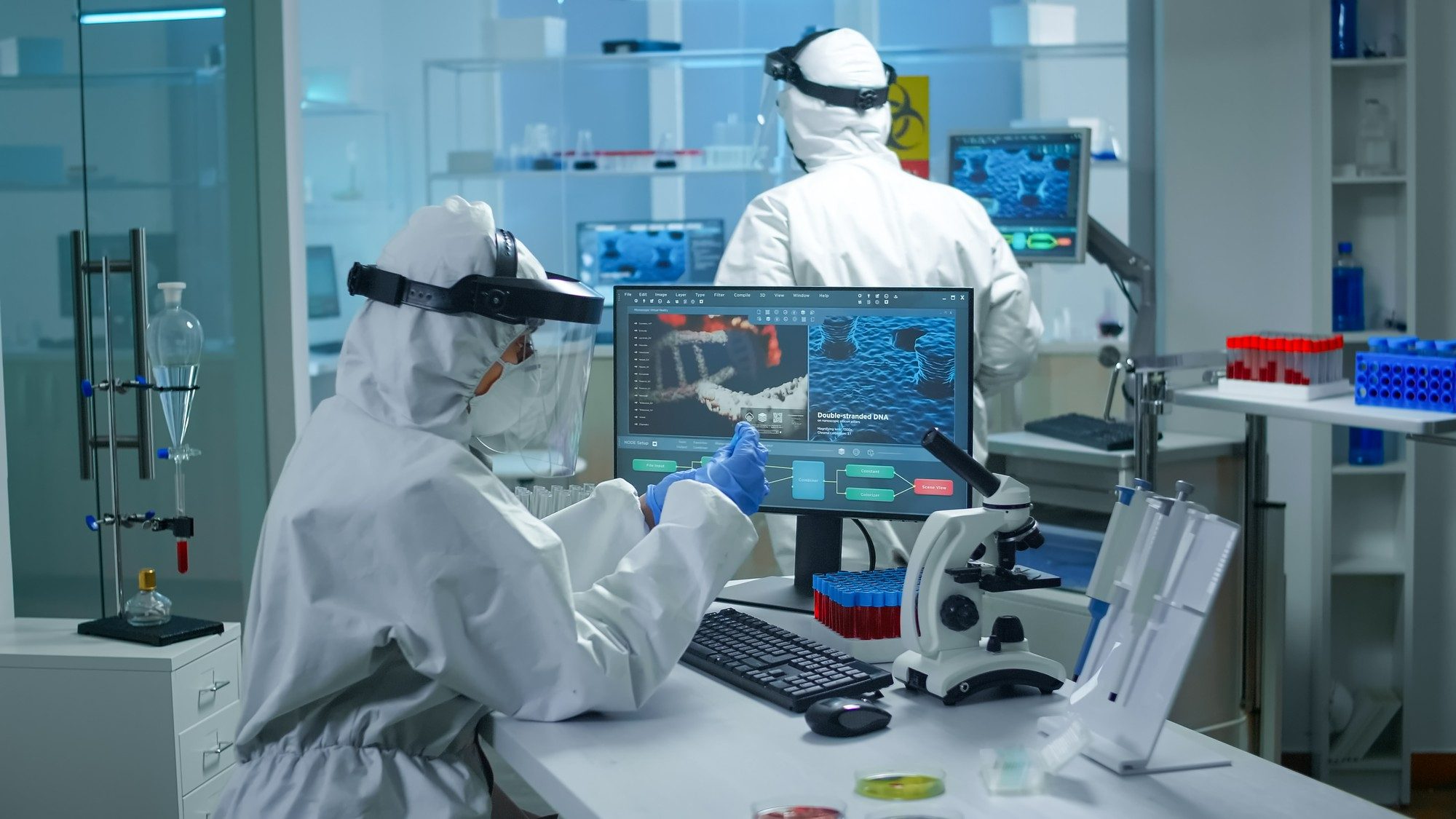 chemist-doctor-ppe-suit-working-pc-while-lab-technician-bringing-her-blood-samples